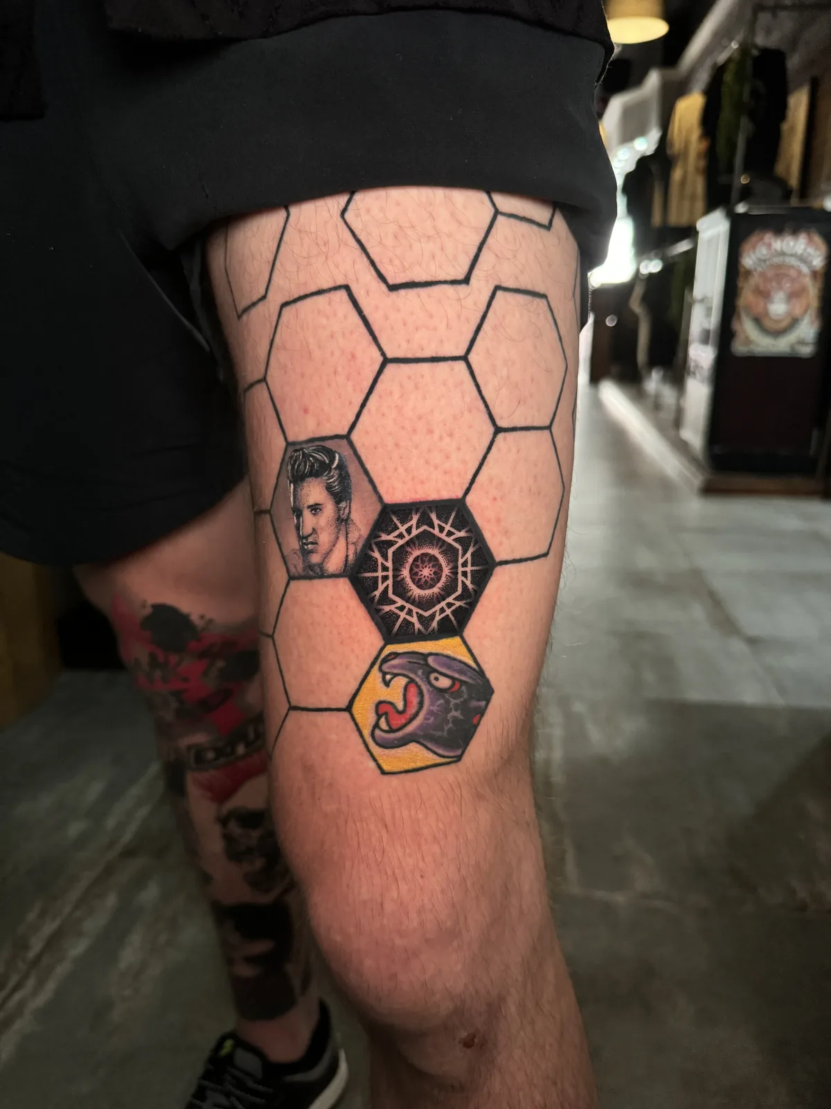 Honeycomb hexagon grid tattoo with portrait, mandala and panther panels on the thigh by Scotty Massa