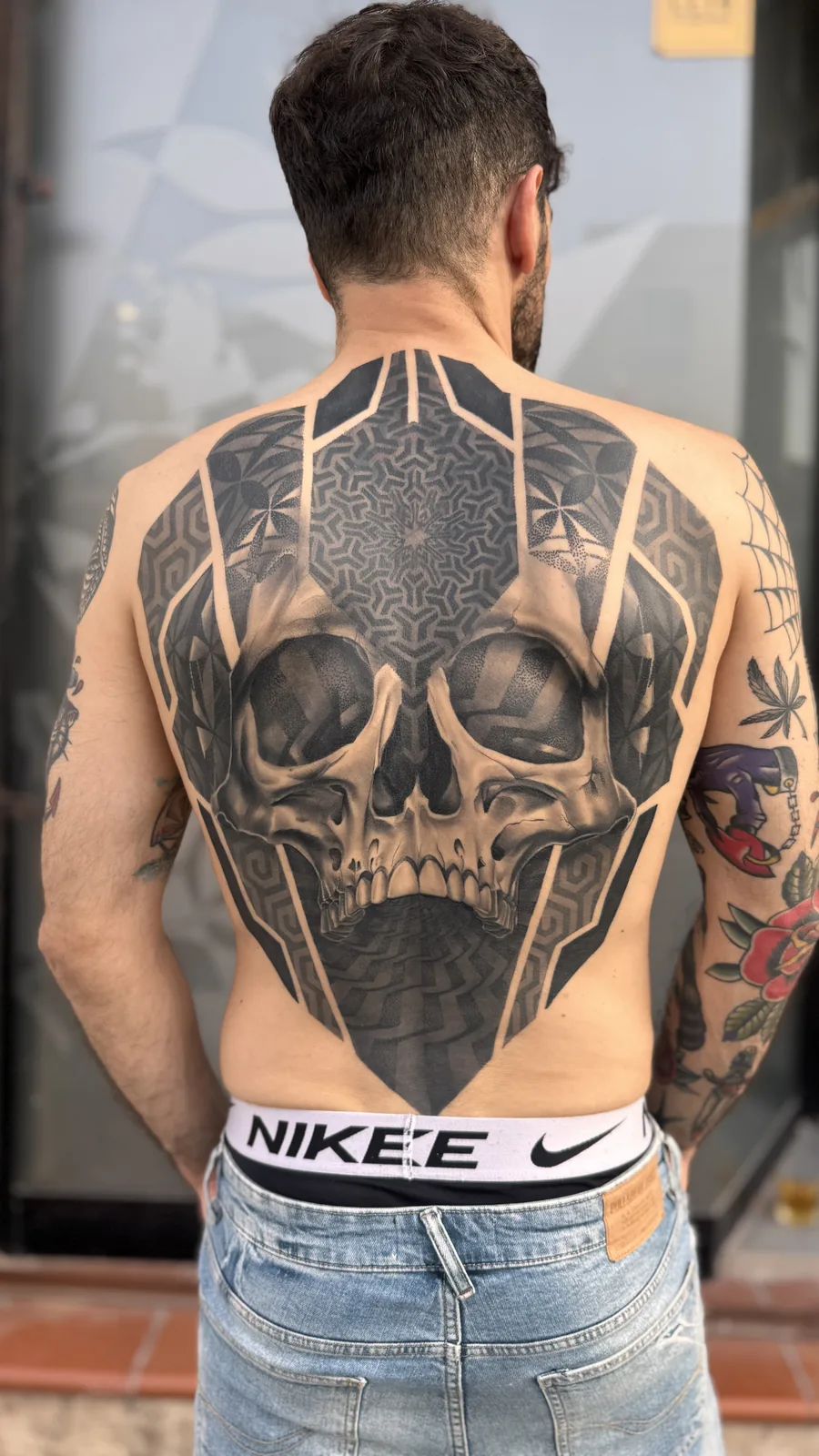 Blackwork skull held inside hand-drawn geometry, full back tattoo by Scotty Massa