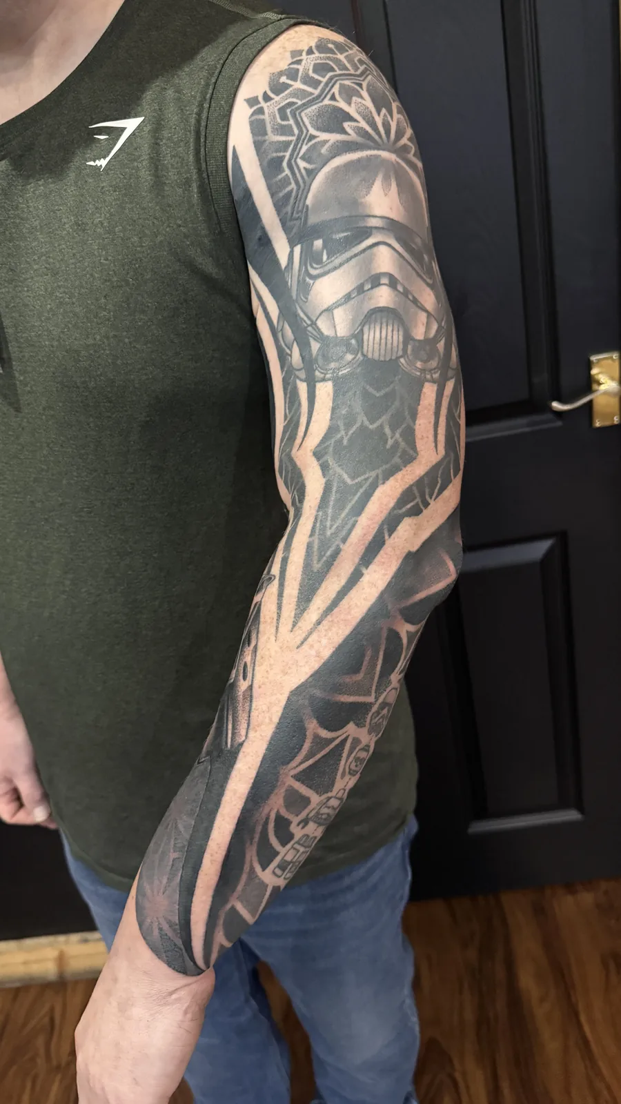 Stormtrooper helmet crowned with mandala work, geometric blackwork full-arm tattoo sleeve by Scotty Massa